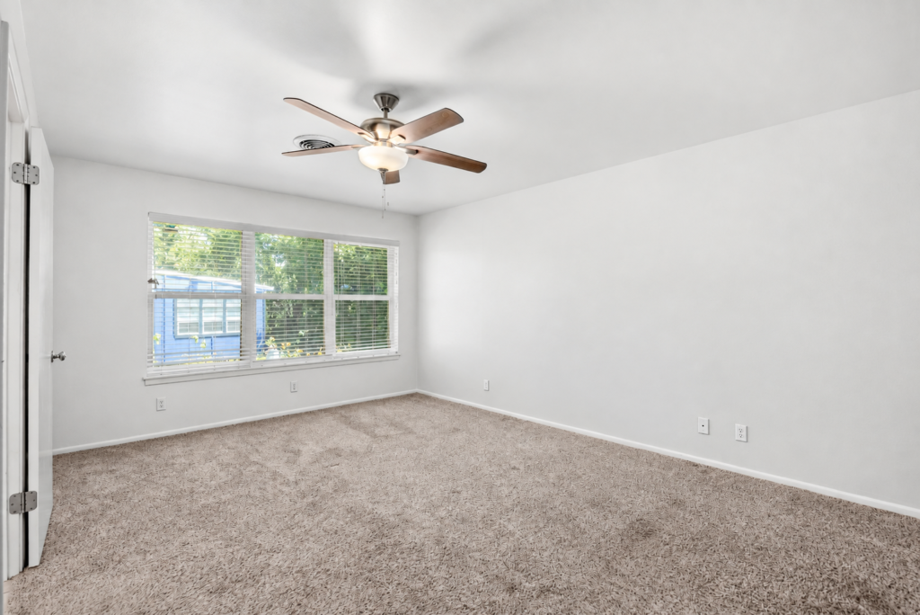 Carpeted bedroom with ceiling fan and freshly painted soft white walls