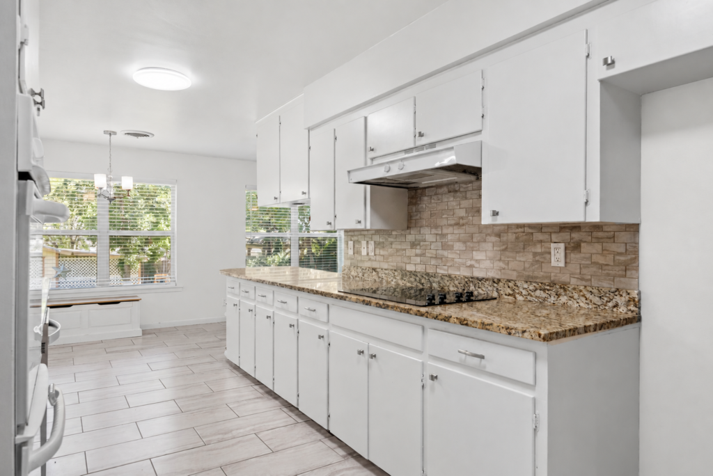 Kitchen with tile backsplash, range and breakfast nook beyond