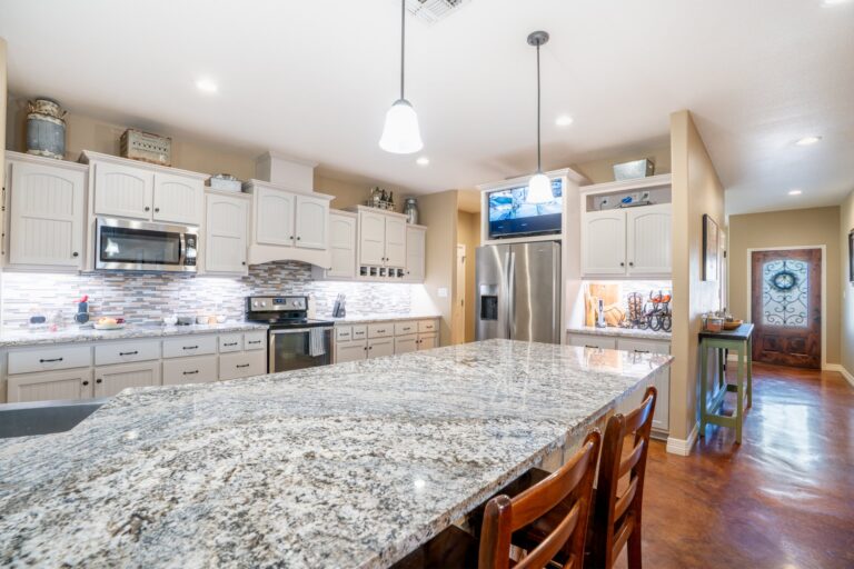 Granite island, custom cabinetry and glass mosaic backsplash in the kitchen at 119 Fannin Drive, Kerrville