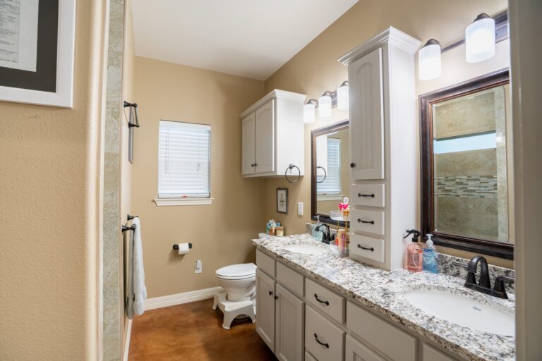 Double granite vanity with center linen tower in the primary bath at 119 Fannin Drive, Kerrville